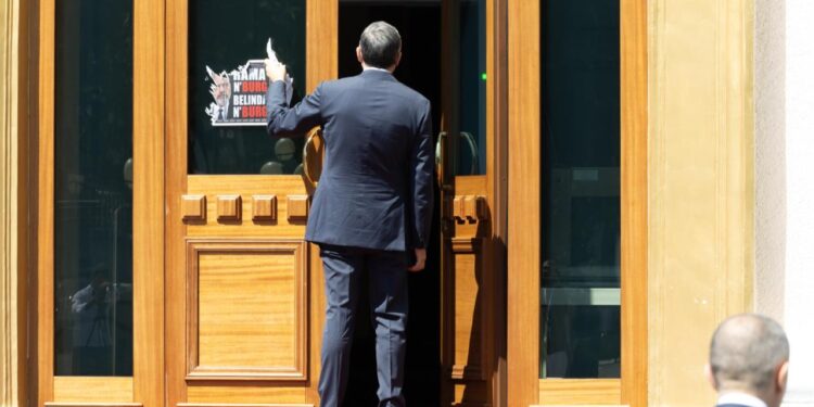 Fotolajm: Deputetët e PD ngjisin parullën e protestës në hyrje të Kuvendit, Blendi Klosi ndërhyn për ta hequr